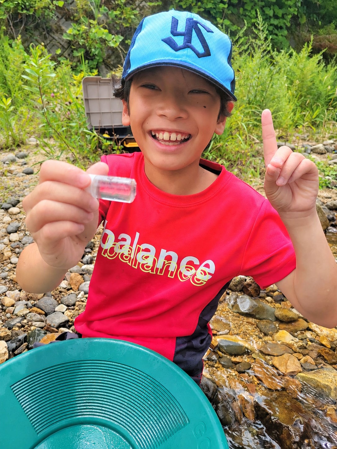 採取した砂金の小瓶を手に笑顔を見せる子ども